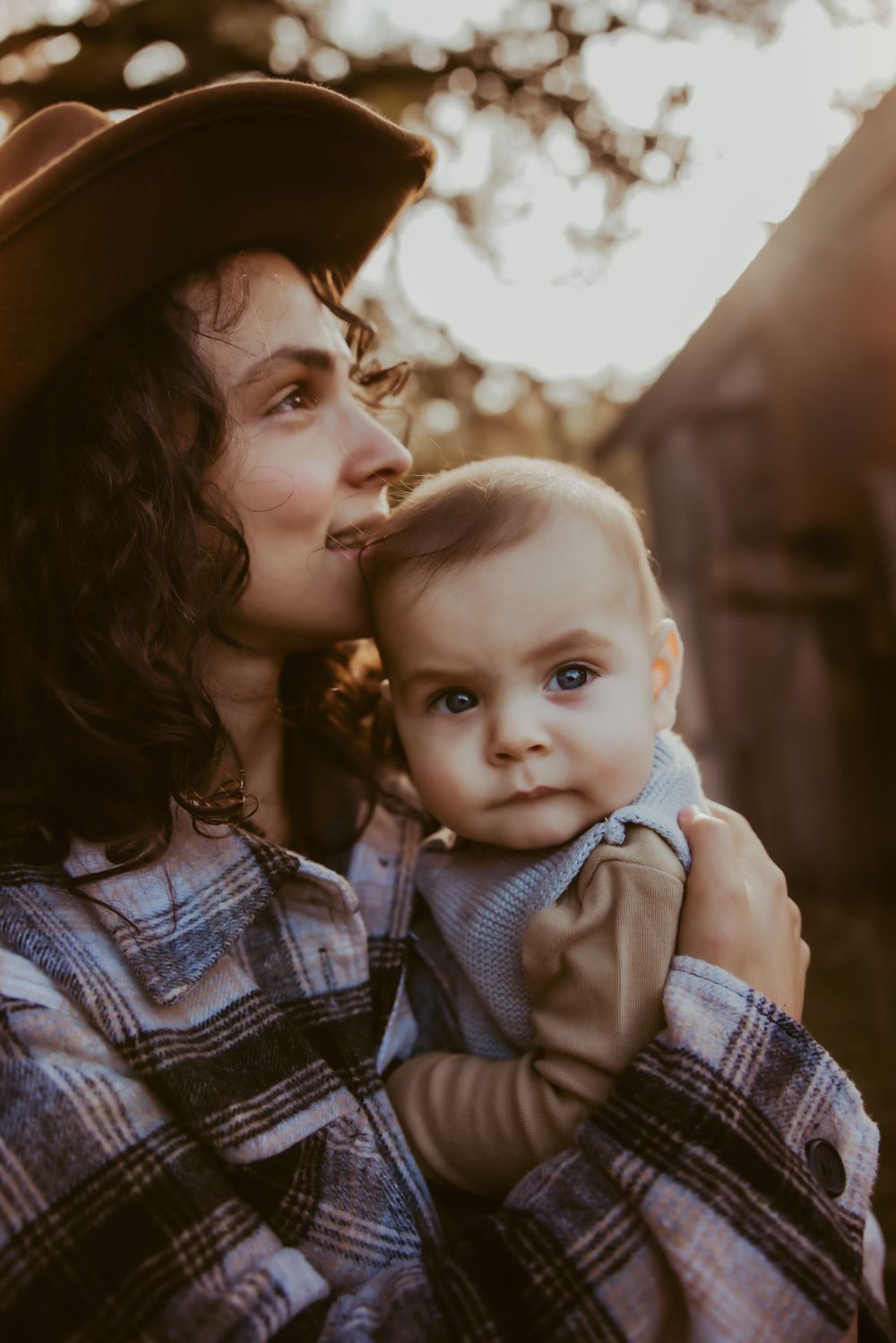 A tender moment between parent and child captured in a warm moody light against a cloudy background.