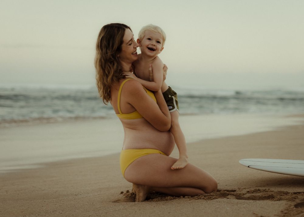 Joyful moments shared between parent and child while sitting on a sandy beach at sunset.