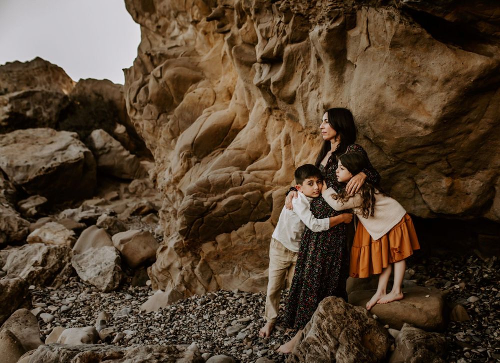 Intimate family photoshoot among dramatic rock formations at the beach.