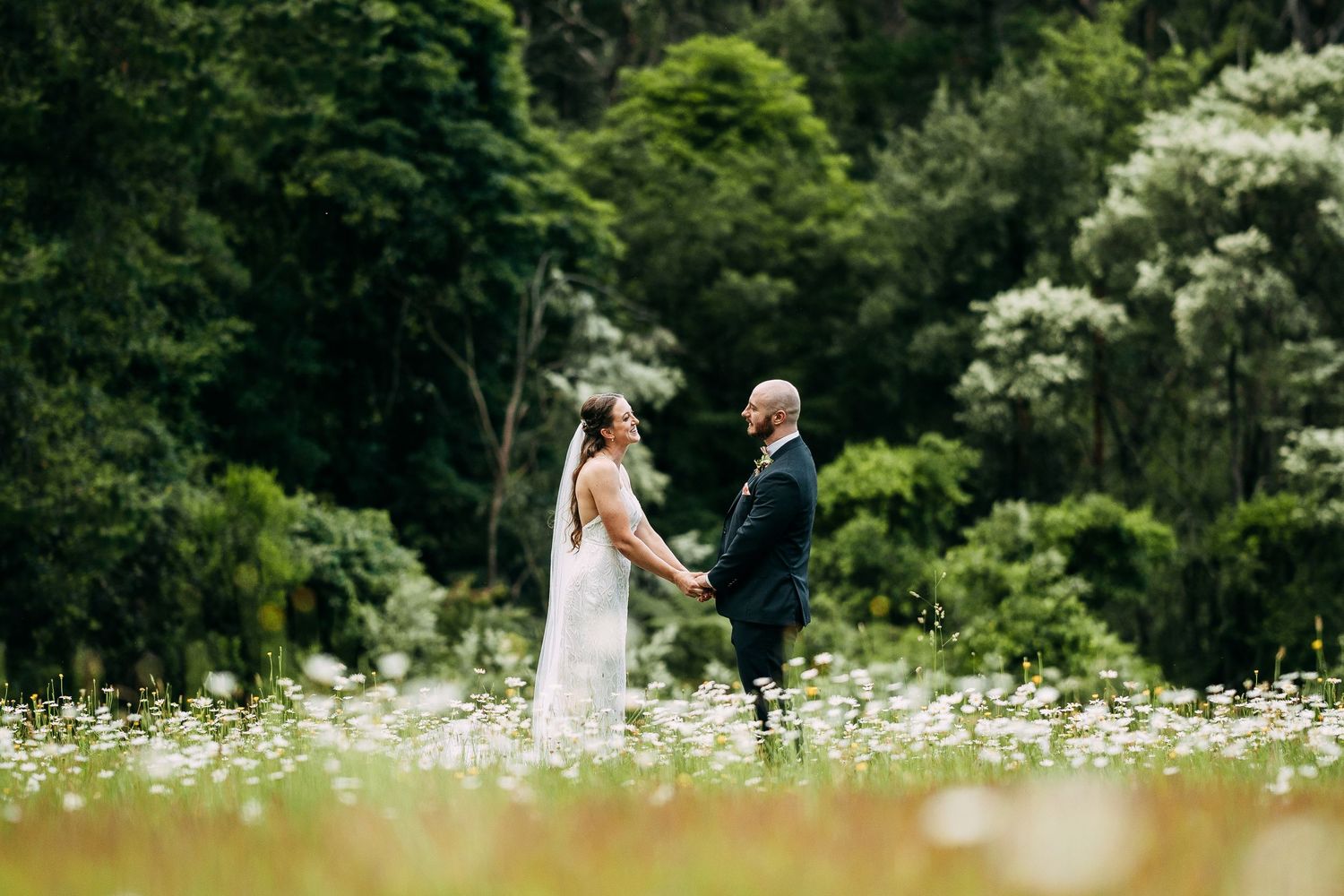 A romantic moment in a field of white daisies surrounded by lush greenery.
