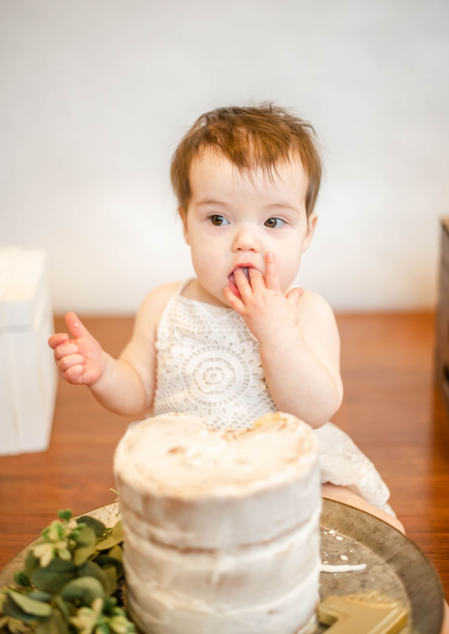 Small white smash cake with lace detail sits ready for first birthday celebration.