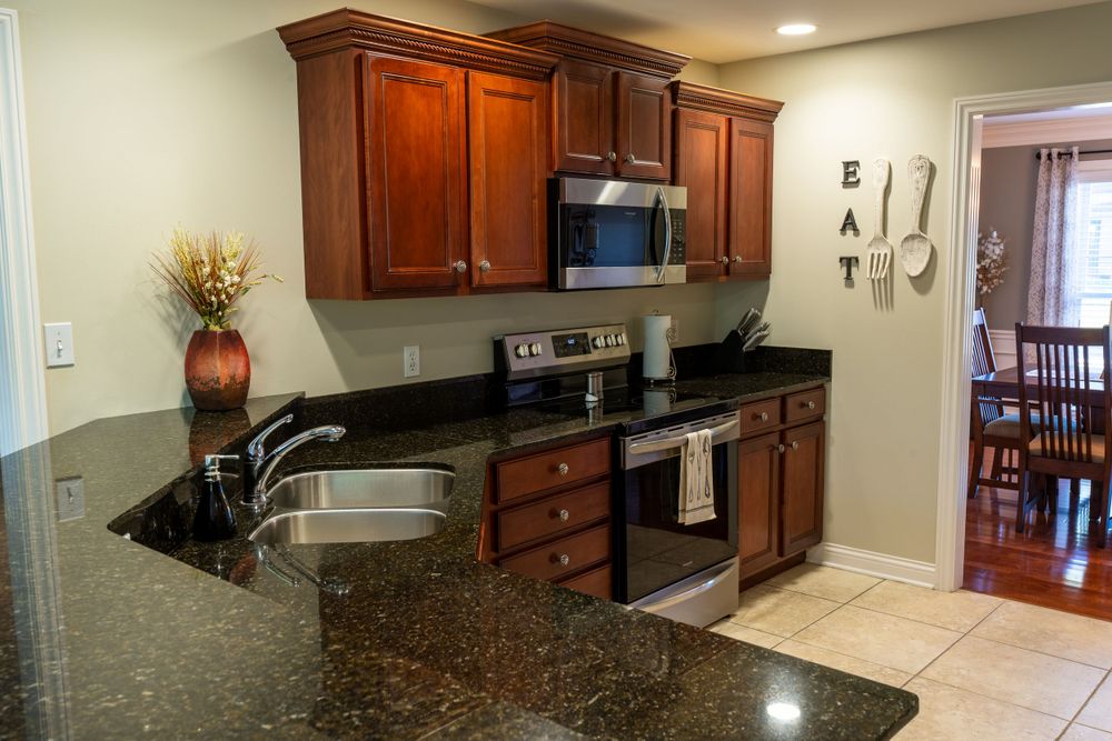 Modern kitchen with dark wood cabinets, black granite countertops, and stainless steel appliances.