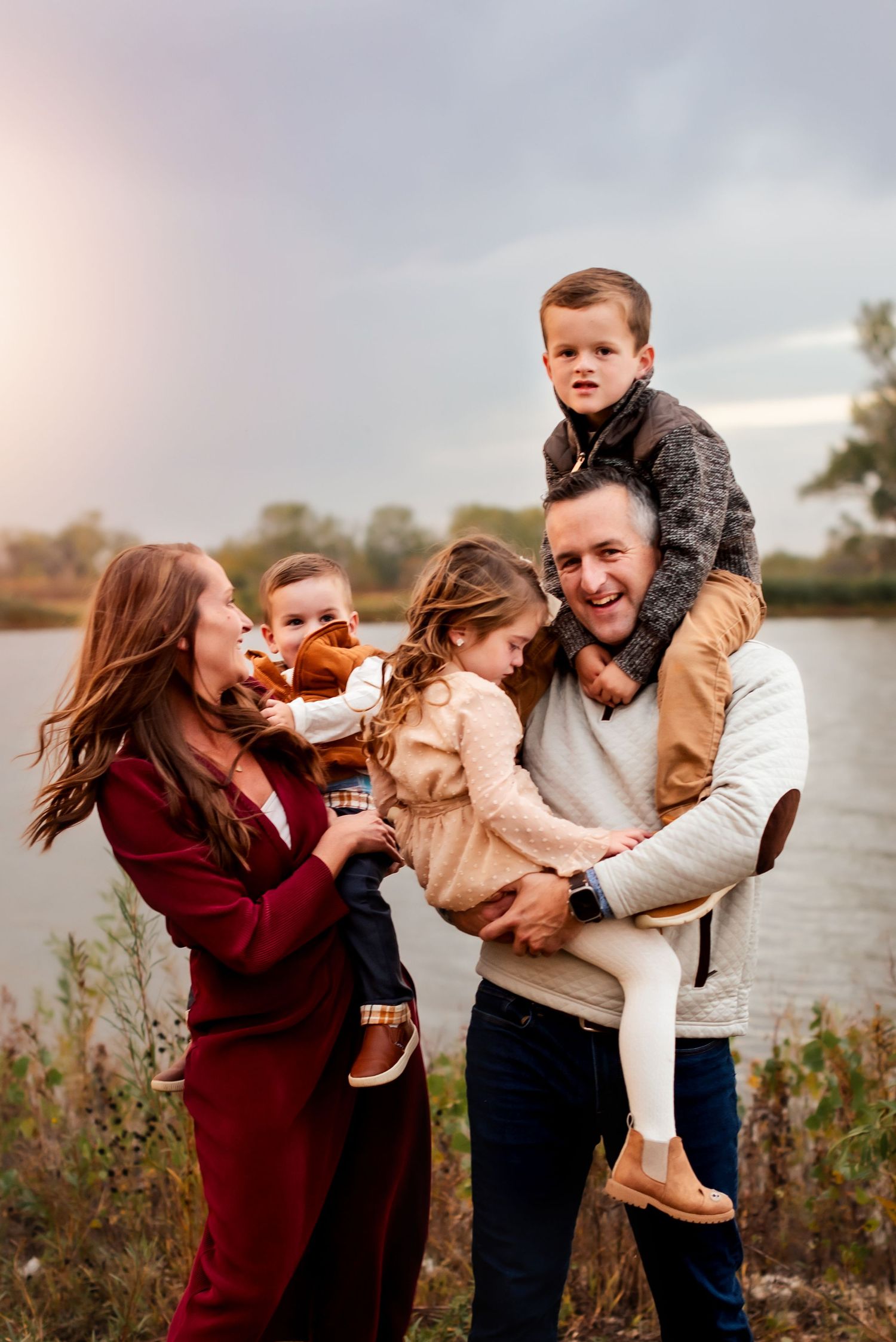 A happy family shares joyful moments together by a lake during sunset.