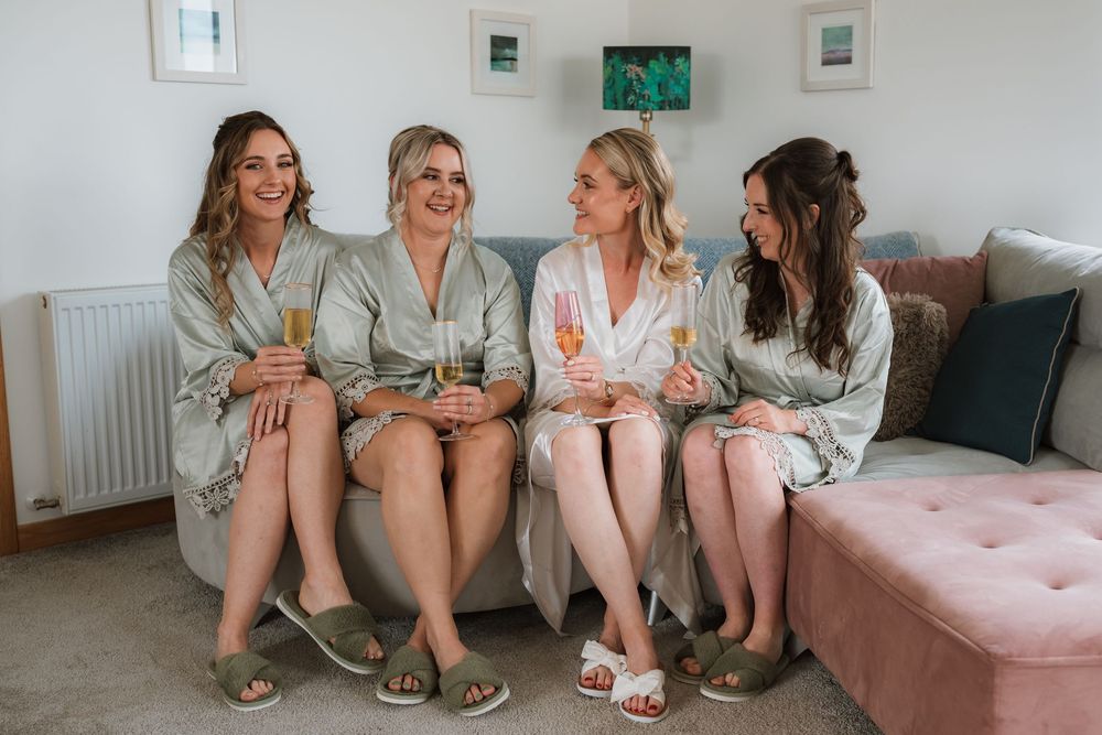 Group sitting together on pink couch wearing matching floral robes during special occasion gathering.