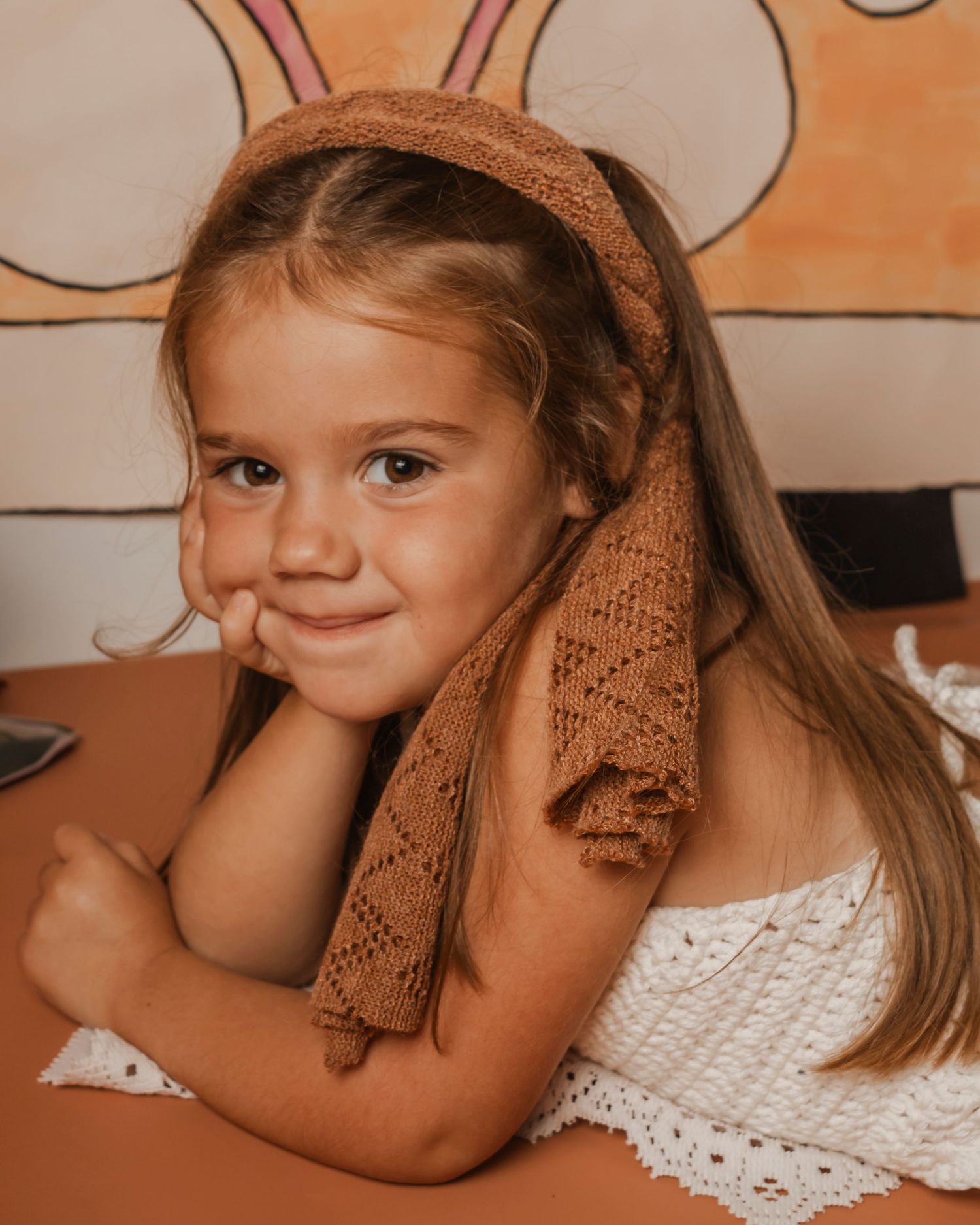 A young girl lays on her stomach resting her chin on her hand