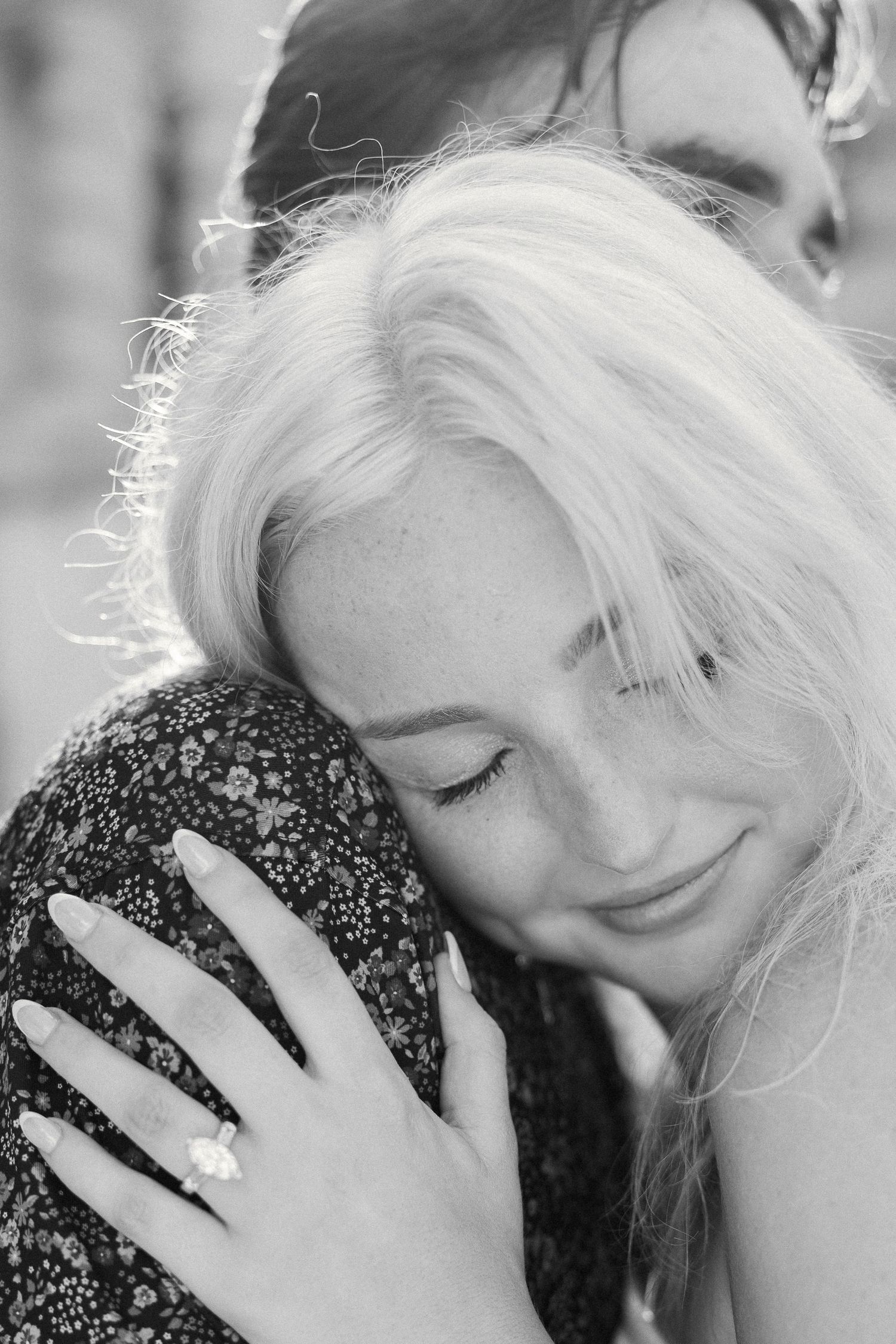 Close-up black and white portrait showing tender embrace with floral pattern fabric.