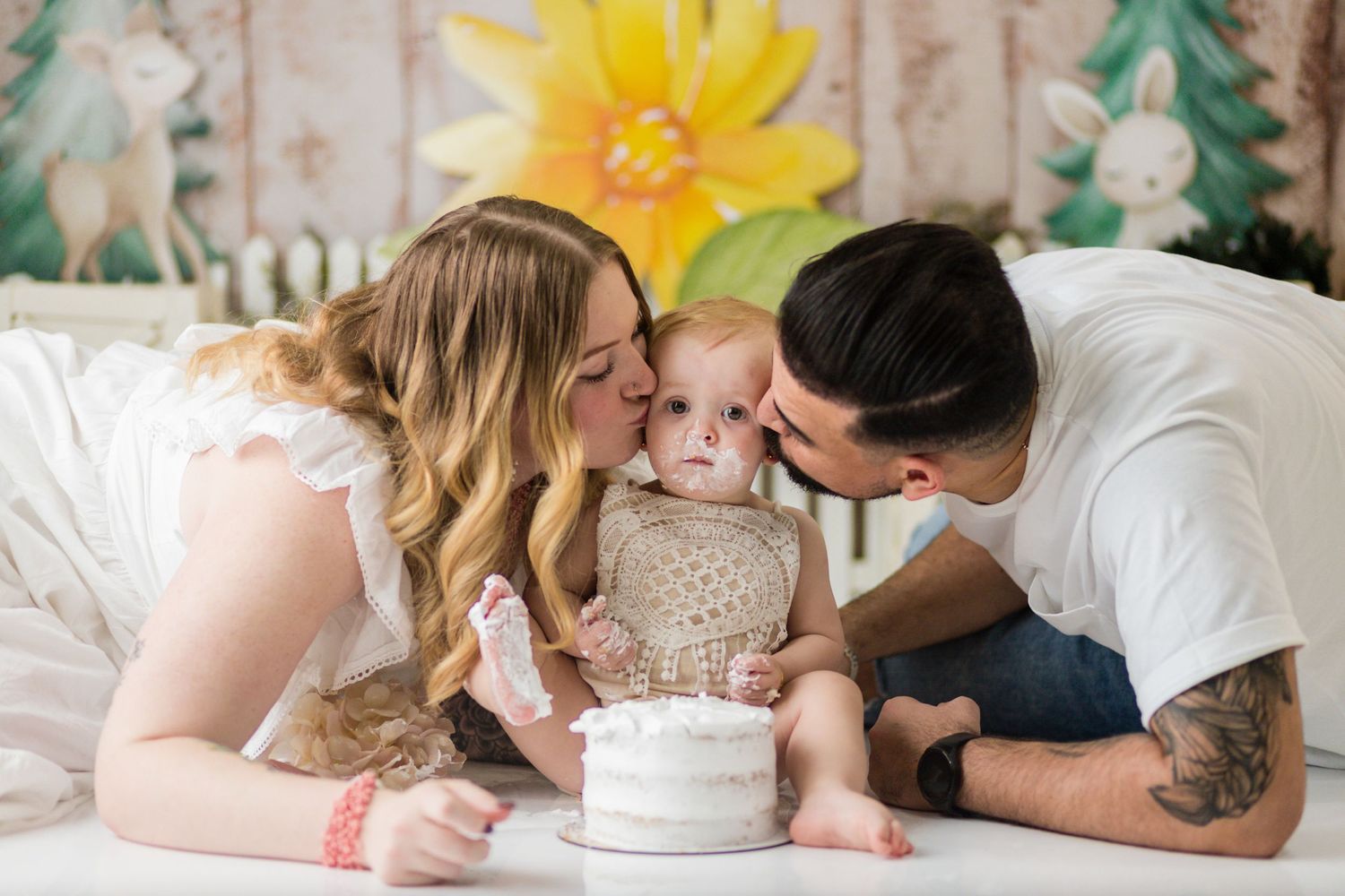 Sweet family moment around small white cake with rustic spring backdrop.