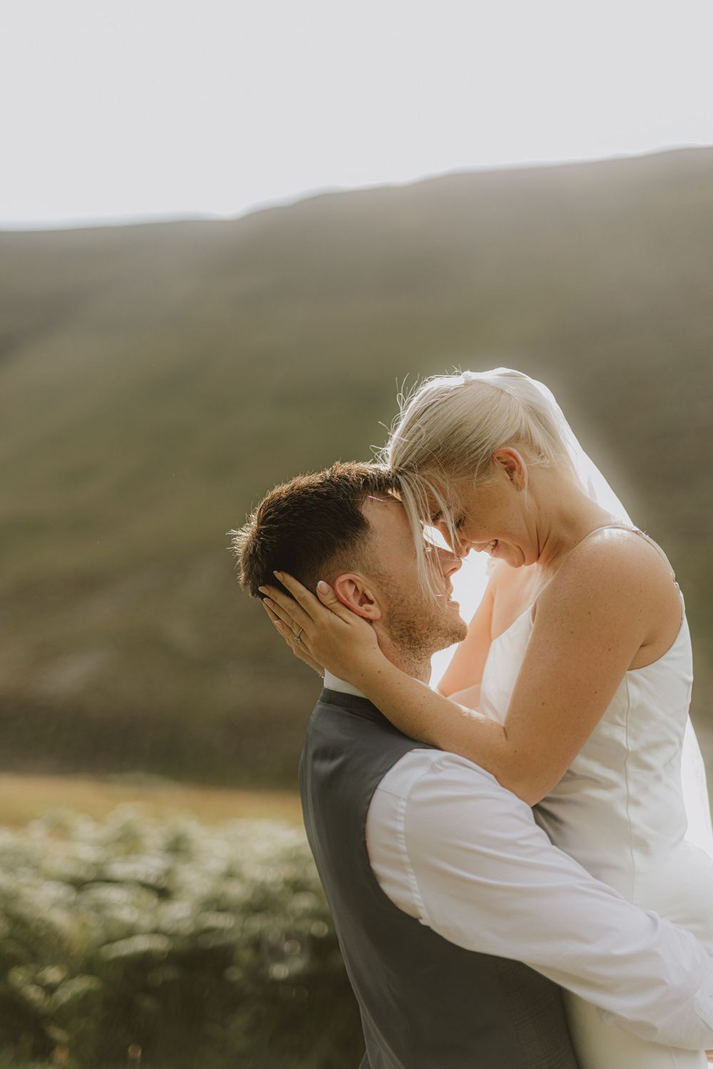 Romantic sunset wedding portrait with mountains and dramatic lighting.