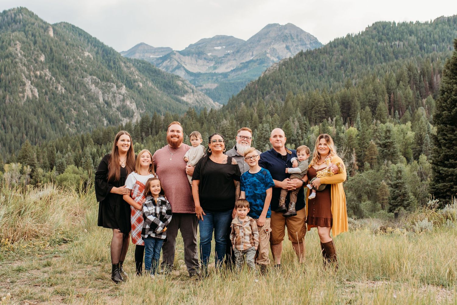 Group portrait against a stunning mountain landscape with evergreen forests and peaks in the background.