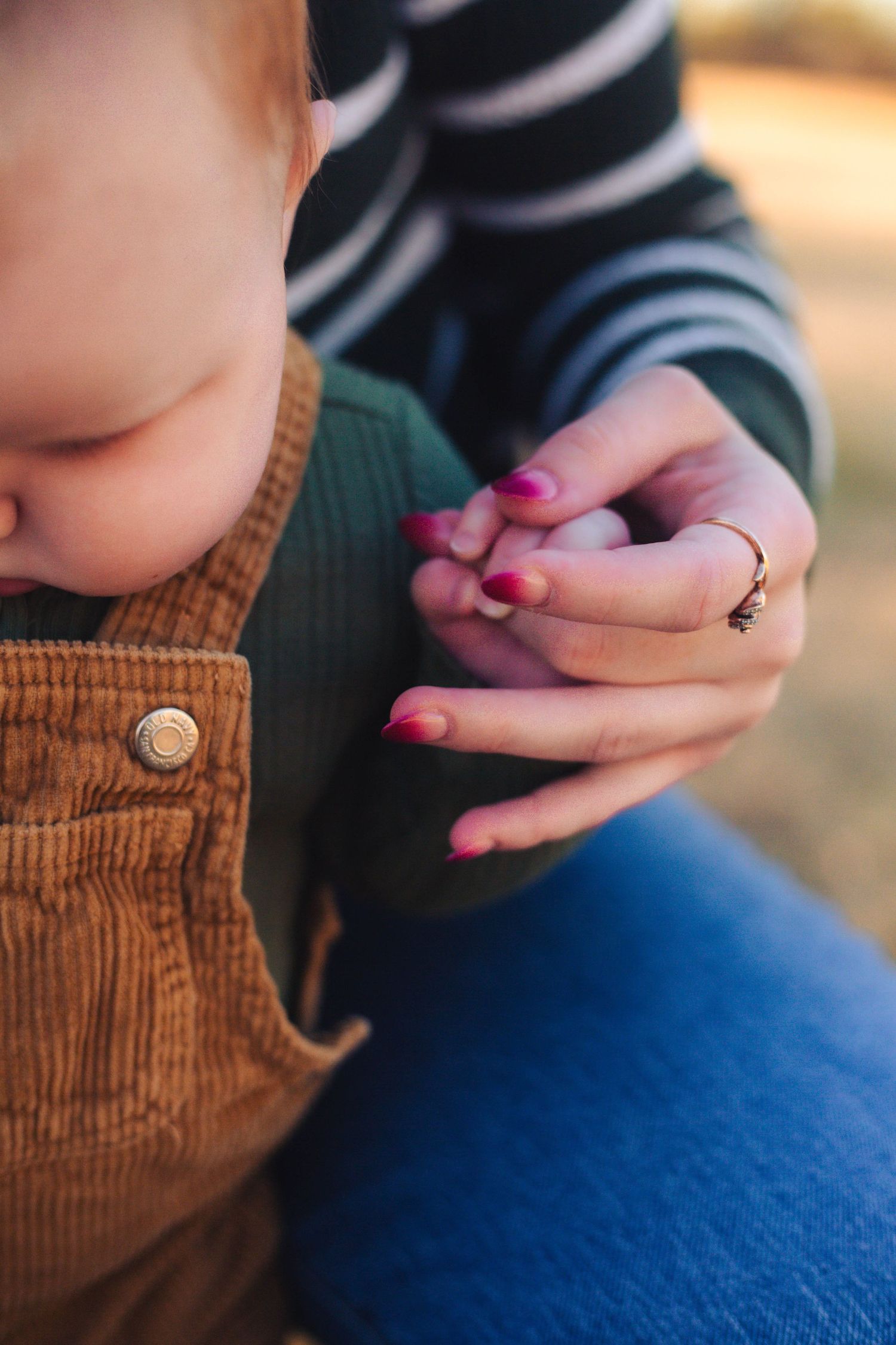 Newborn detail shot with tiny fingers wrapped around mom’s hand in Norman