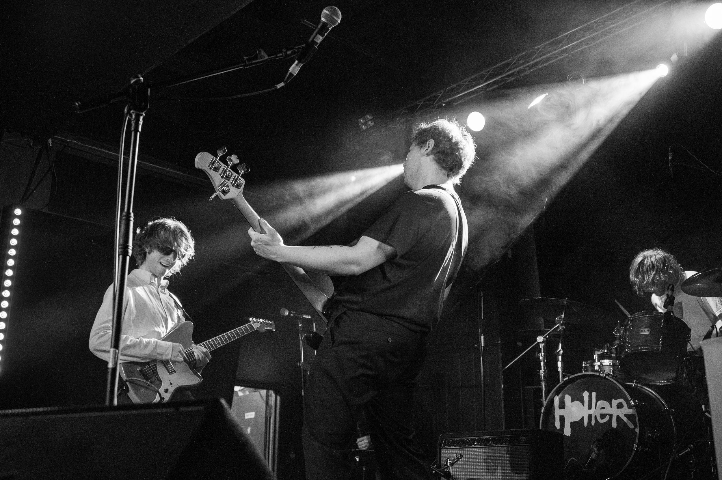 Black and white concert photo showing band members performing with dramatic stage lighting.