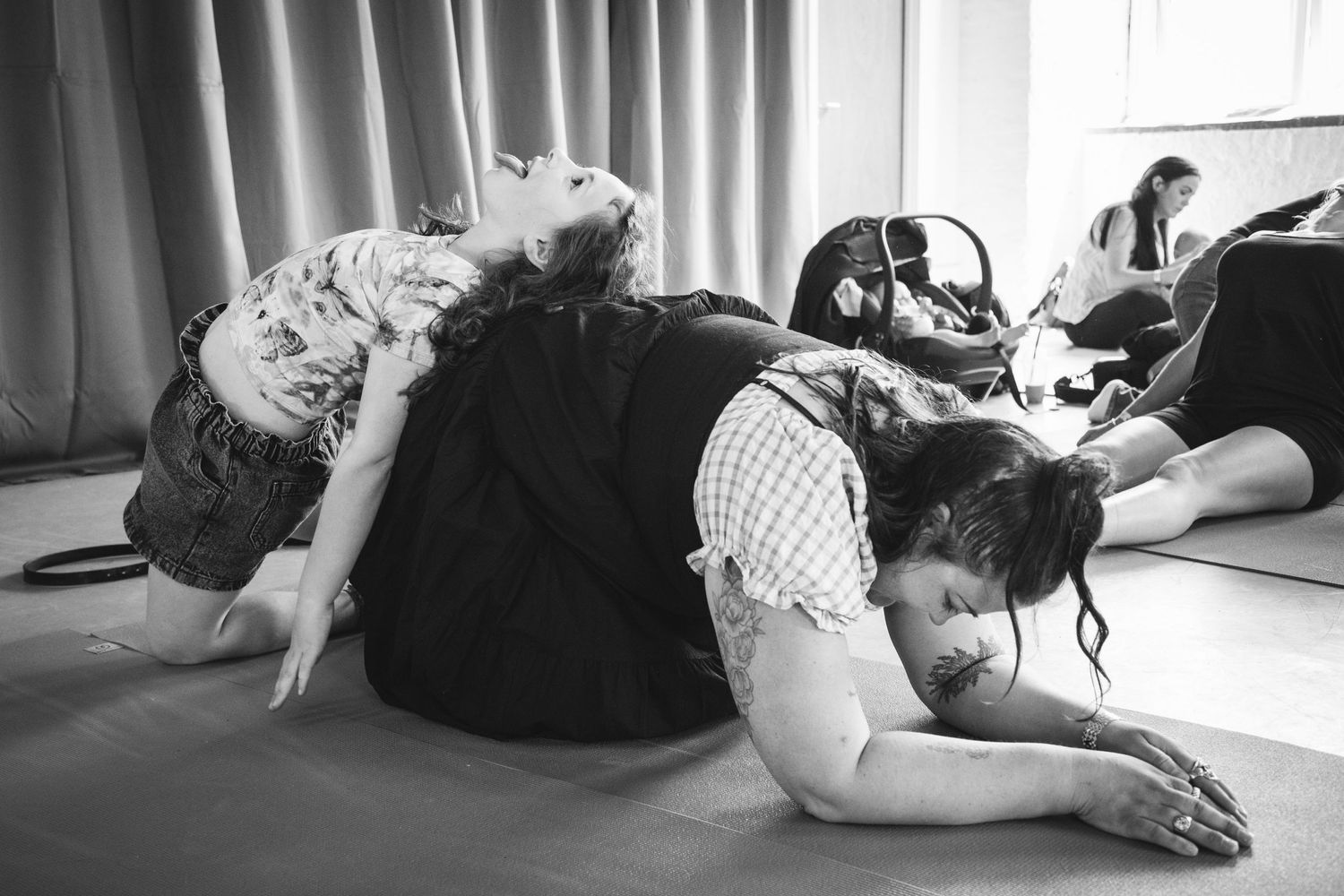 Group stretching and exercising together in a studio setting with babies joining the activity.