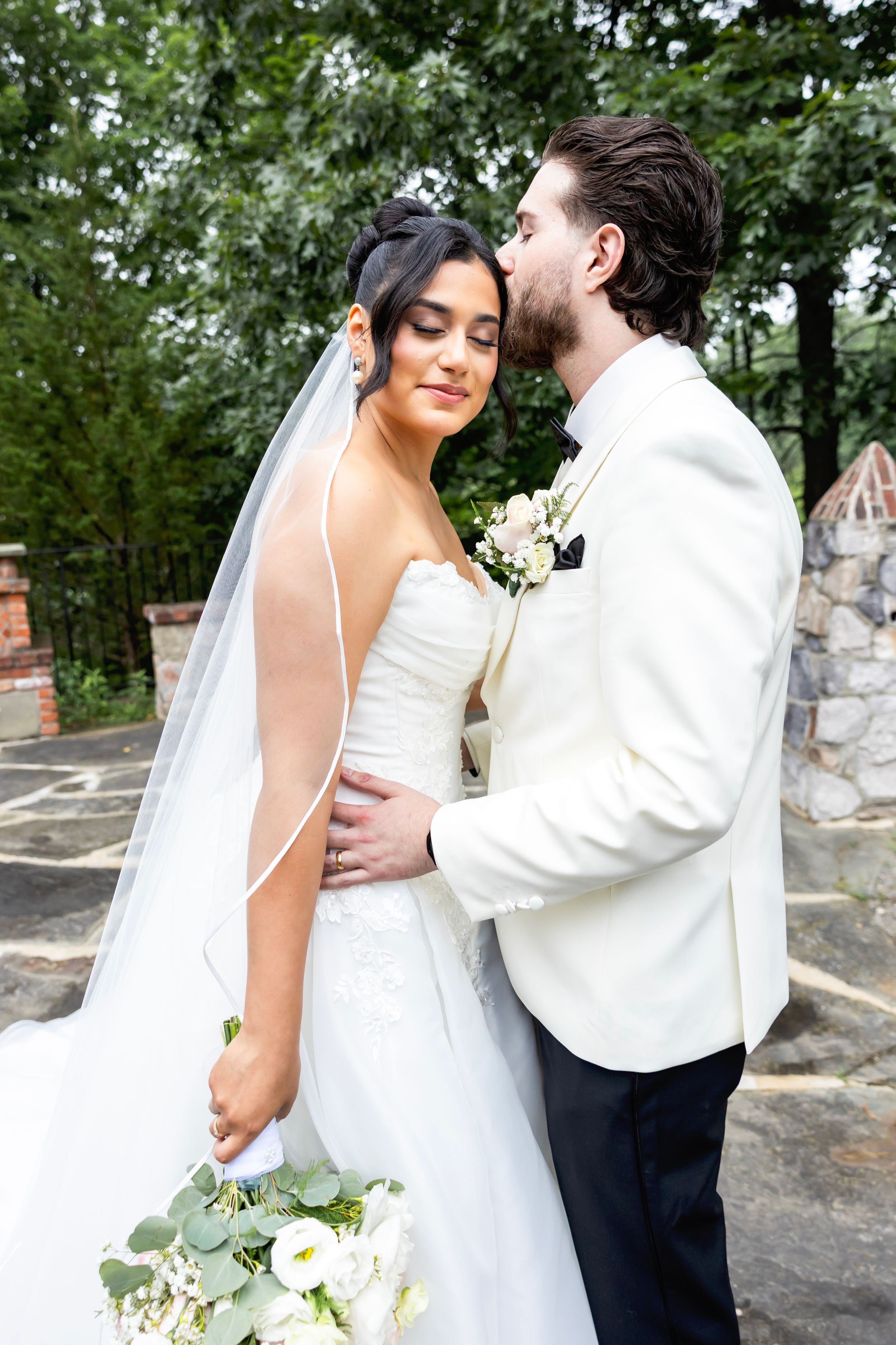 A wedding couple poses for romantic portraits against a stone wall and natural garden backdrop. NJ wedding photographer in Sussex County