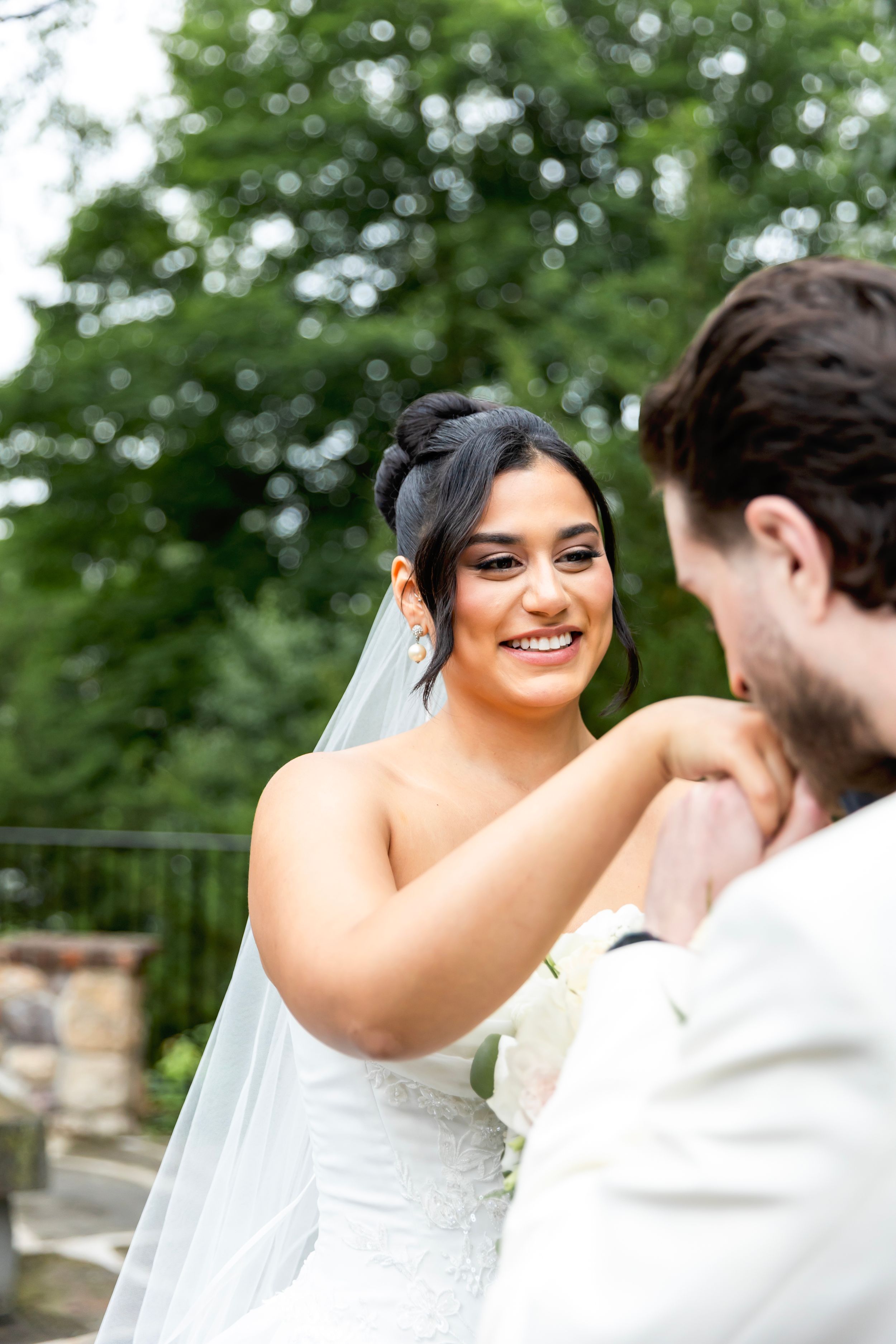 Bride in white lace dress smiling lovingly at groom during outdoor wedding photoshoot. Bergen County Wedding Photographer