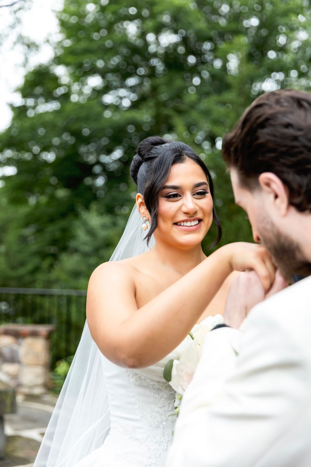 Bride in white lace dress smiling lovingly at groom during outdoor wedding photoshoot. Bergen County Wedding Photographer