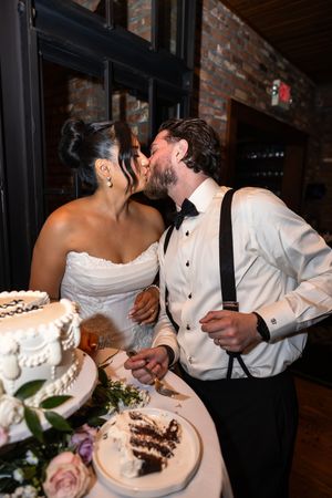 Romantic moment between newlyweds while cutting their wedding cake at reception.