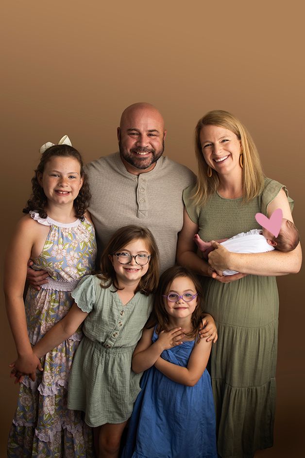 Image of a foster family holding their newborn foster.  Loving Lens Initiative Foster Program.