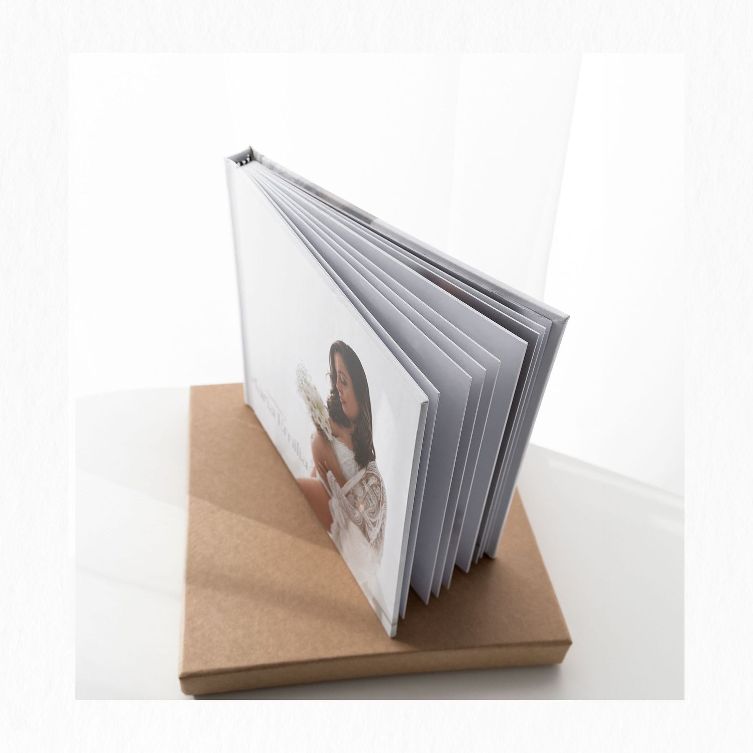 A photo book displayed standing on a brown cardboard box against a white background.