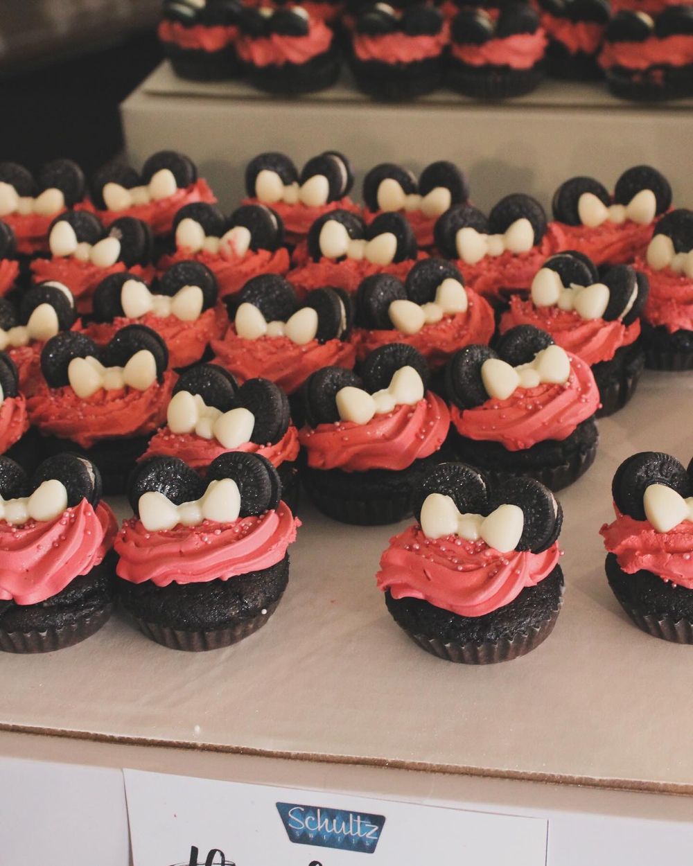Red and black Minnie Mouse themed cupcakes decorated with pink frosting and white polka dot details.
