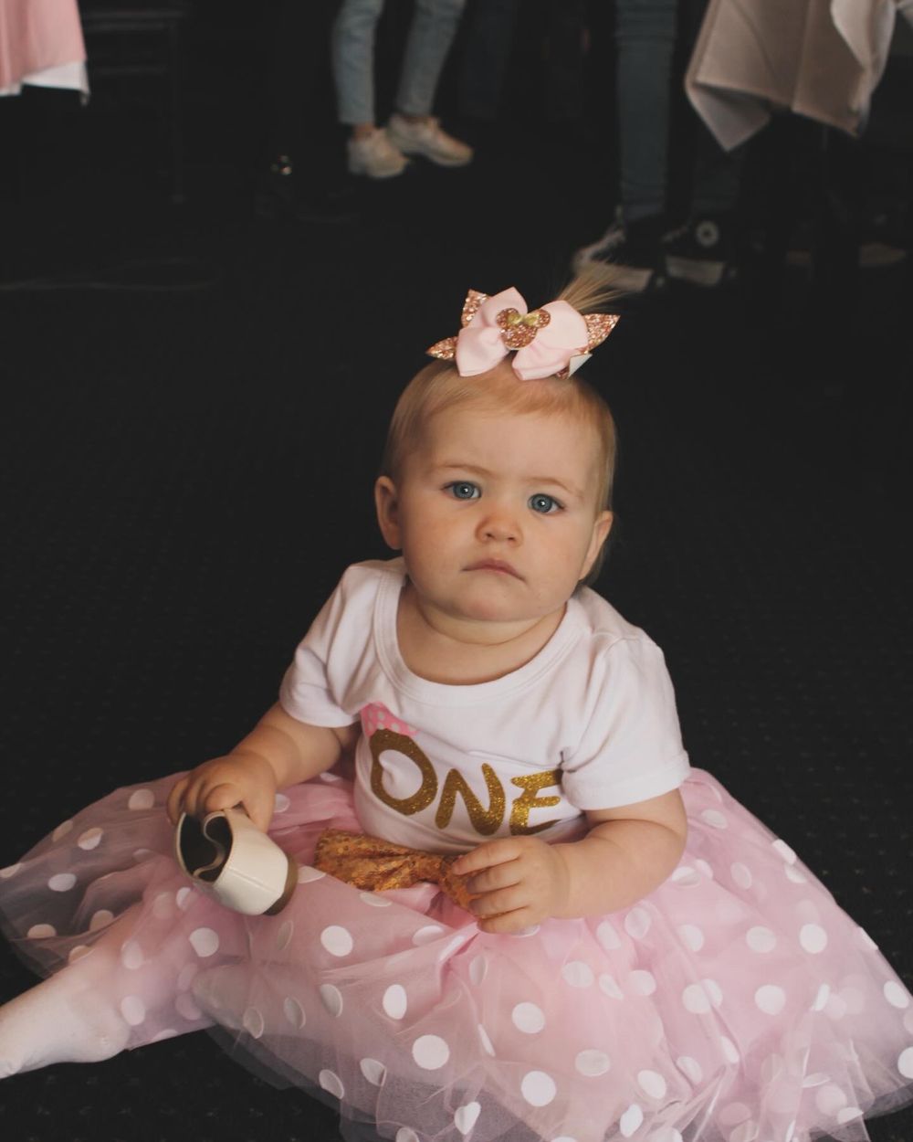 Baby in pink tutu dress and crown sits for first birthday portrait session.