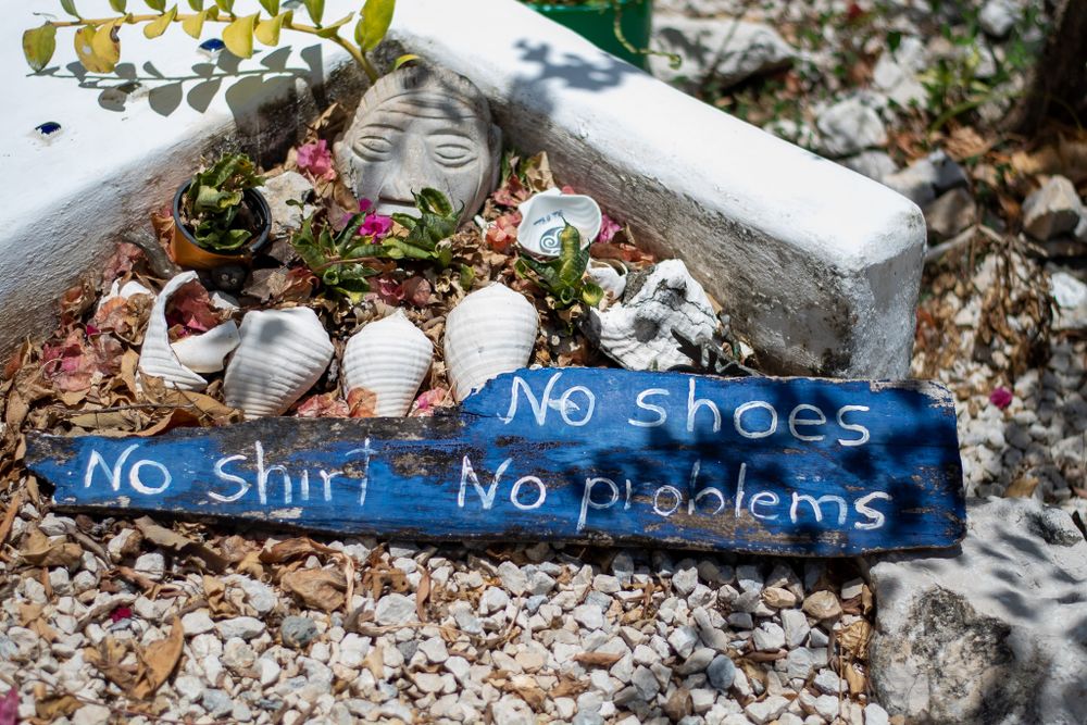 A rustic sign with text 'No shirt, no shoes, no problems' displayed on weathered blue wooden planks.