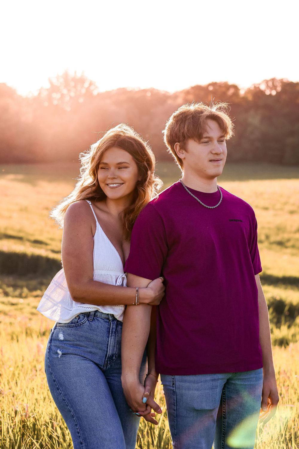 A couple shares a tender moment in a golden field during sunset.