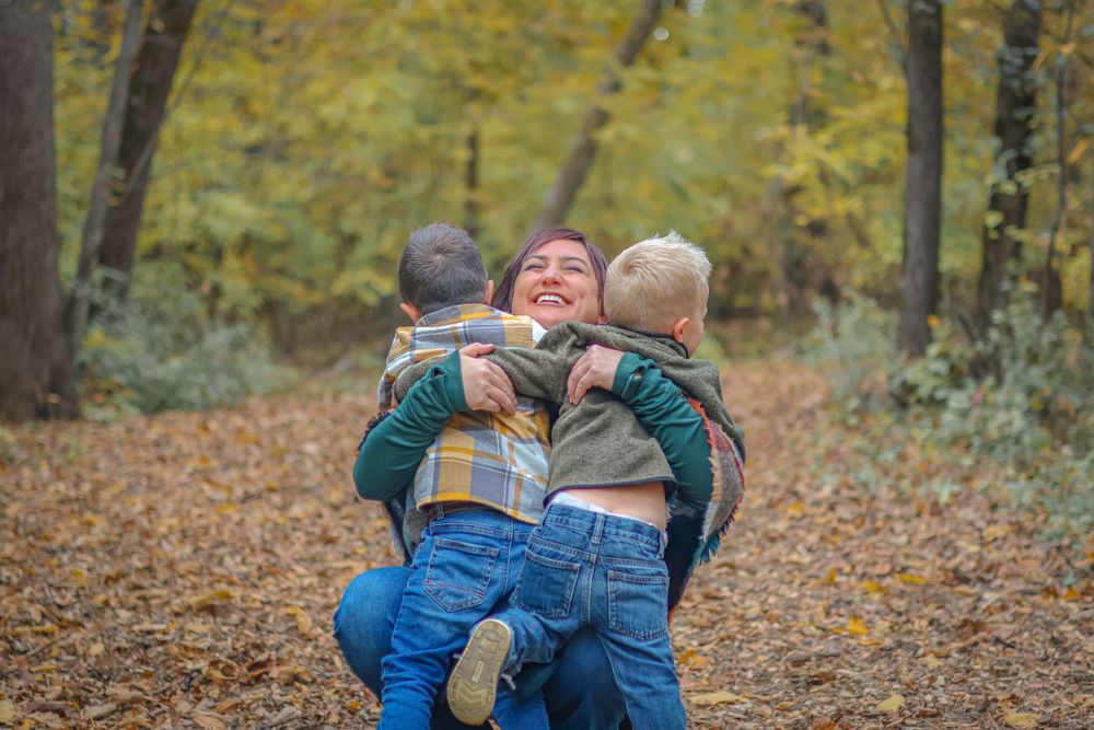A playful moment captured outdoors with family members embracing in autumn woods.