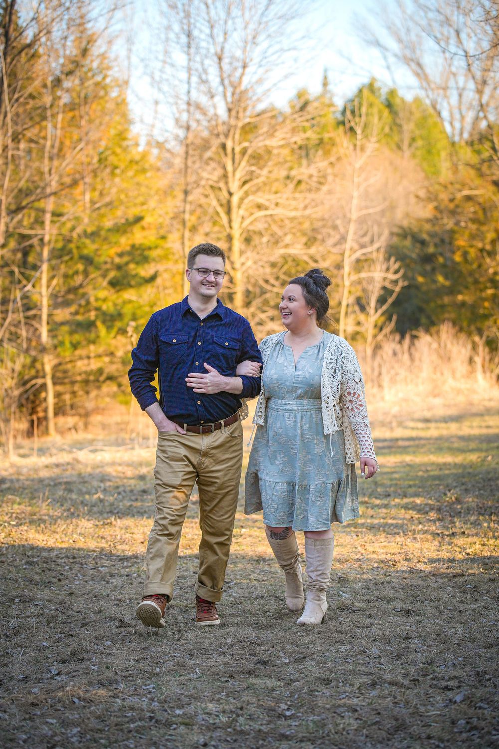 Happy couple walking together through a sunlit autumn field, woman holding mans arm affectionately.