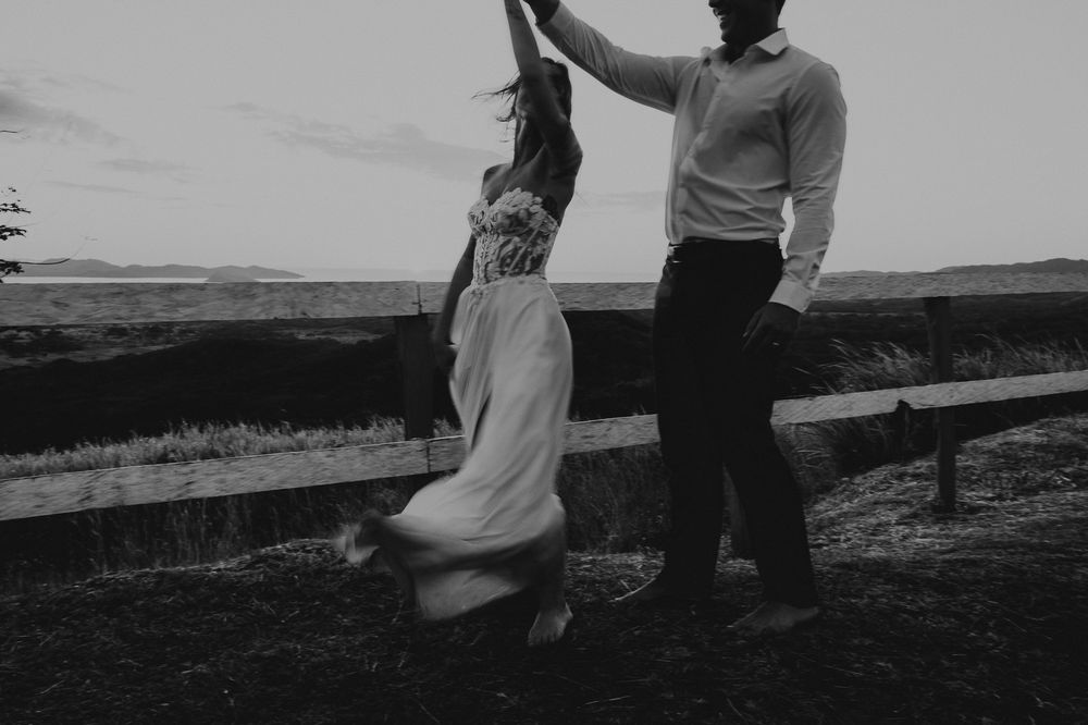 A couple dancing together in a romantic silhouette against a scenic mountain landscape backdrop in black and white.