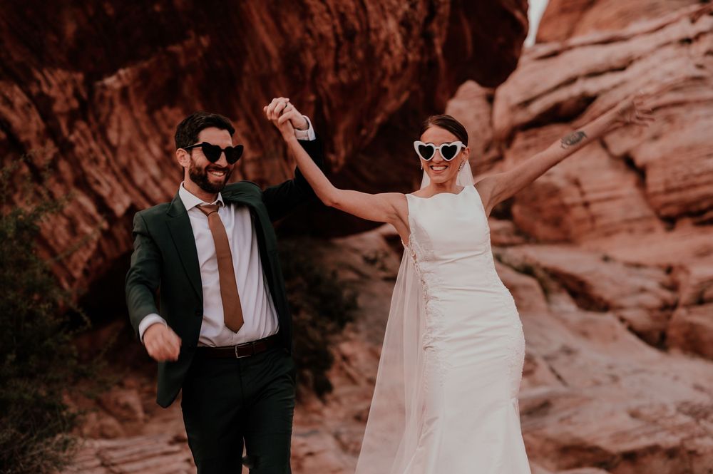 A celebratory moment captured against stunning red rock formations in a desert landscape. un couple de nouveaux mariés qui s'amusent