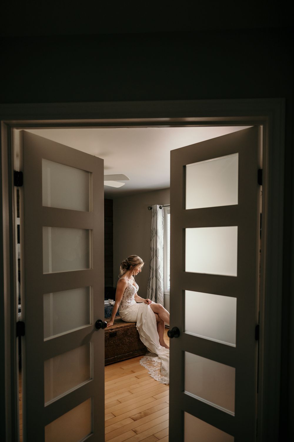 A dark interior view through multiple doorways with geometric window panels and wooden floors.