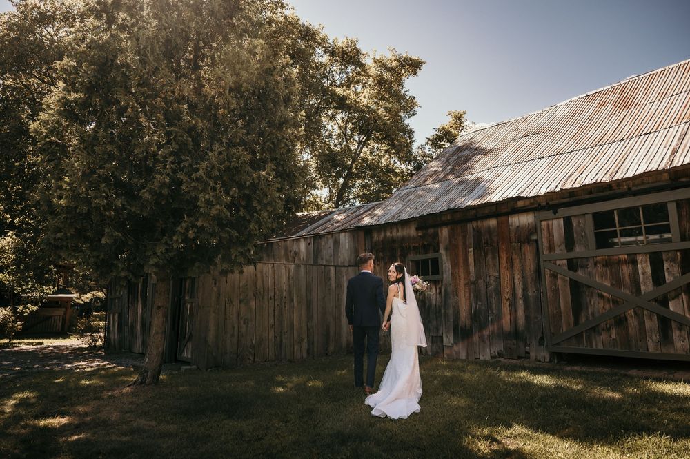 A rustic barn wedding venue with wooden buildings and natural sunlight creating a romantic countryside atmosphere.