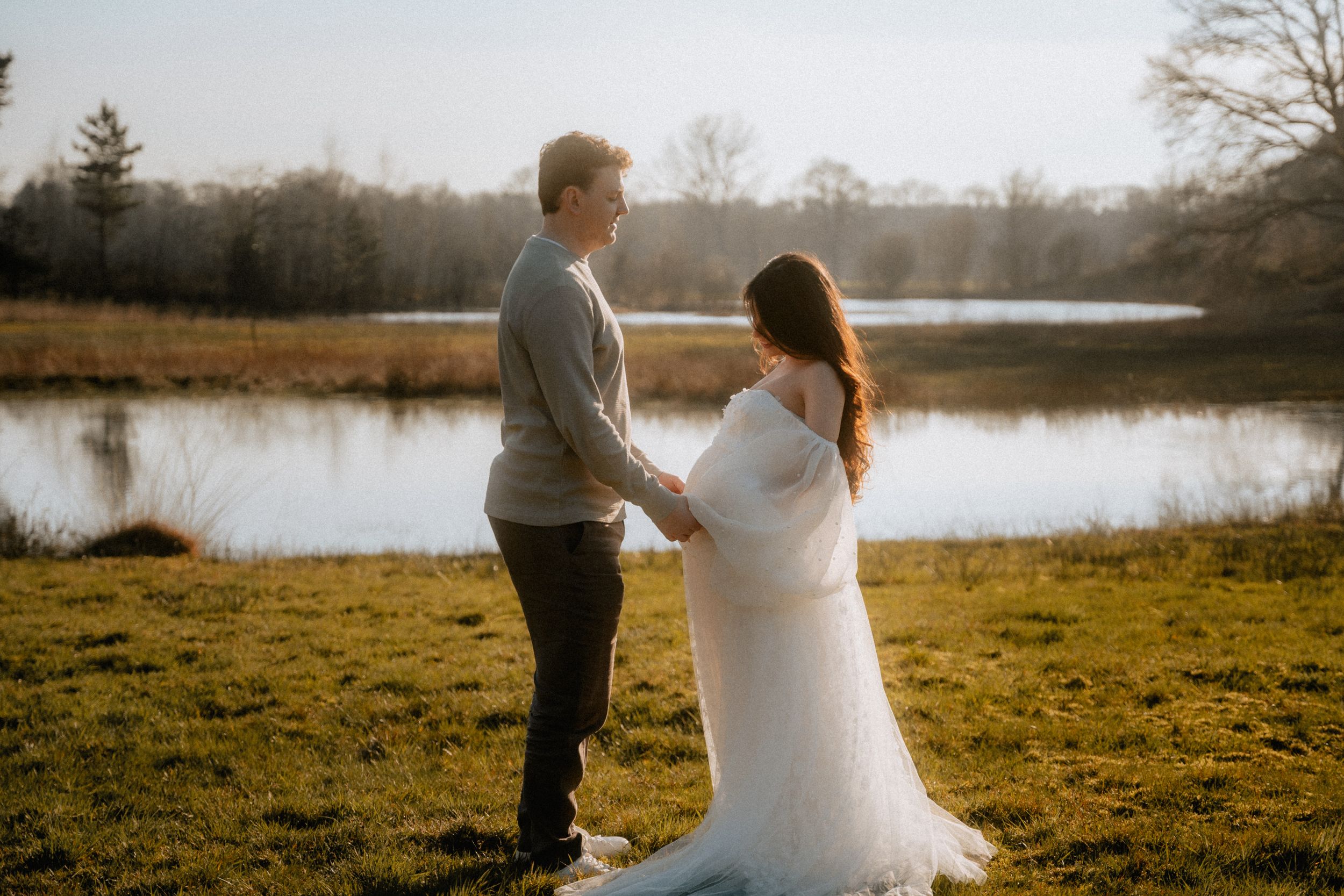 A wedding beautiful couple holding hands in a field with nice warm weather and sun