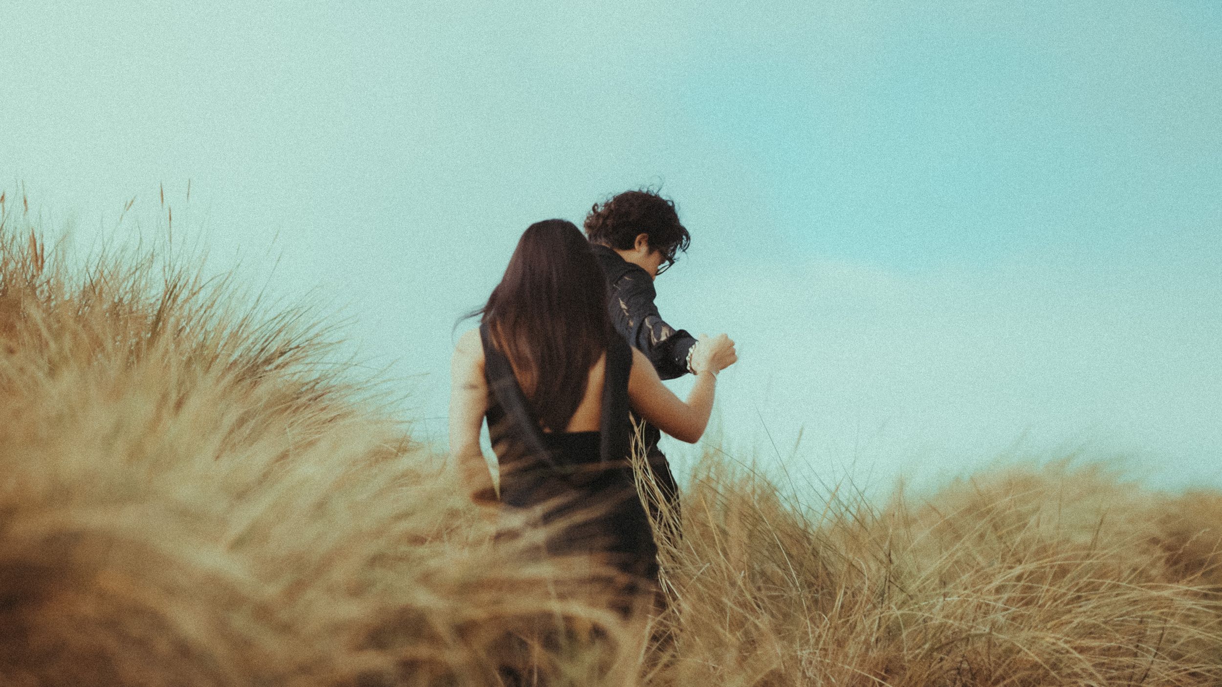 A wedding beautiful couple holding hands in a field with nice warm weather and sun