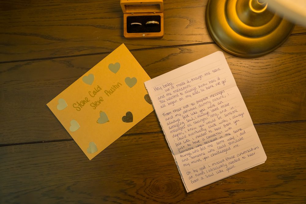 Handwritten wedding note and card with hearts on rustic wooden table.