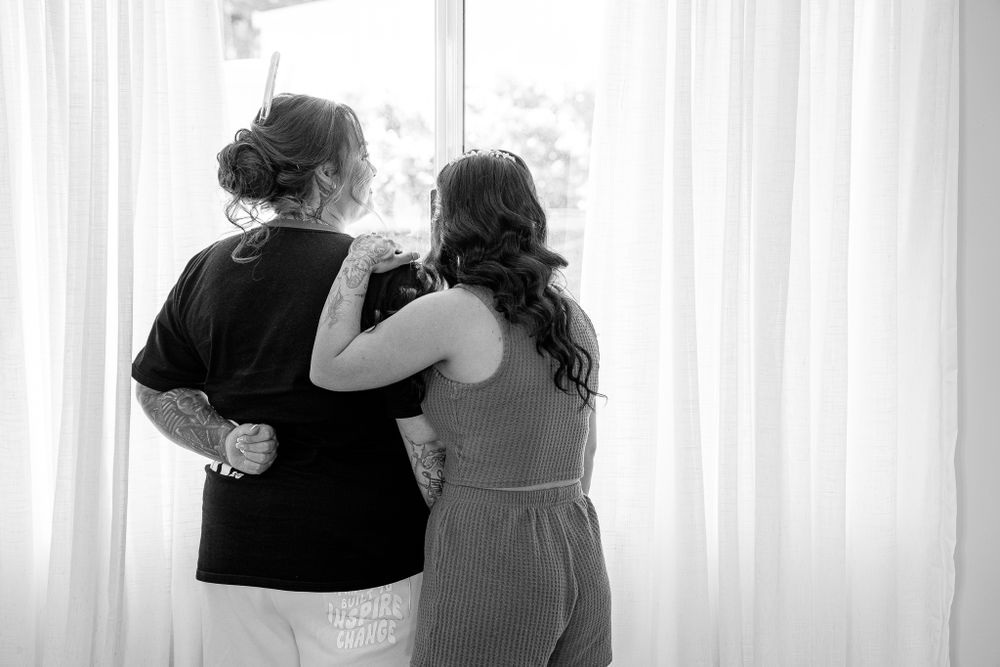 Black and white silhouette of two people standing together by bright window.