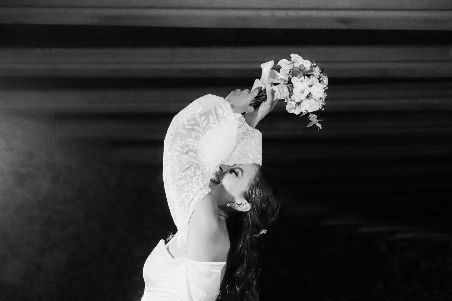 An artistic black and white profile shot of a bride holding her bouquet.