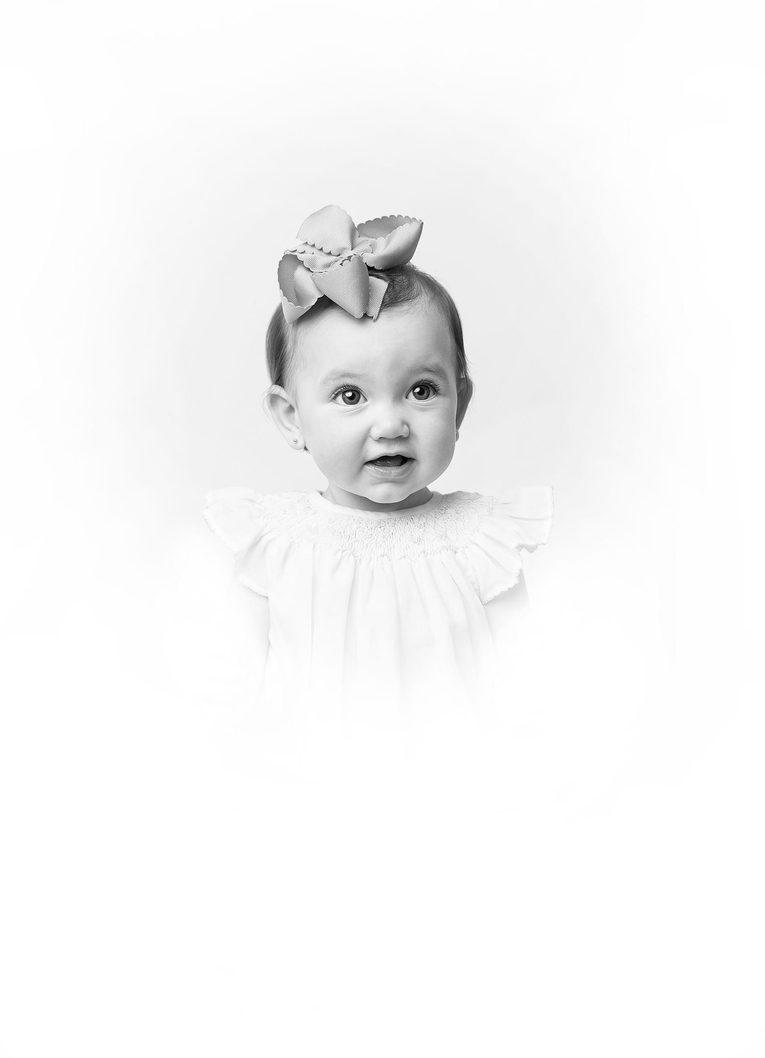 Classic black and white portrait of baby wearing bow headband and white dress.