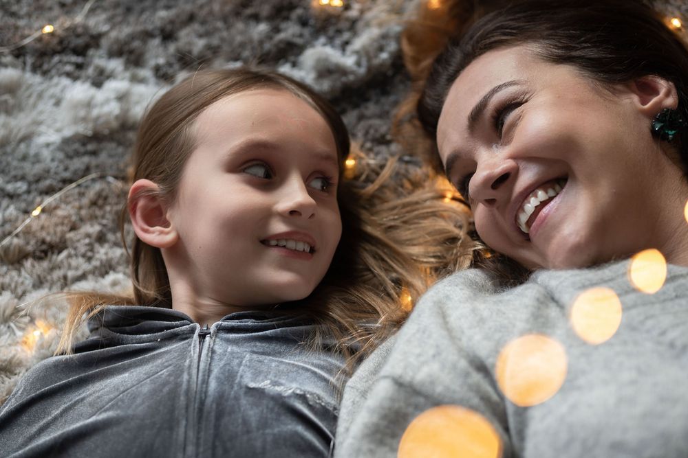Mother and daughter lie on the carpet and enjoy the festive mood.