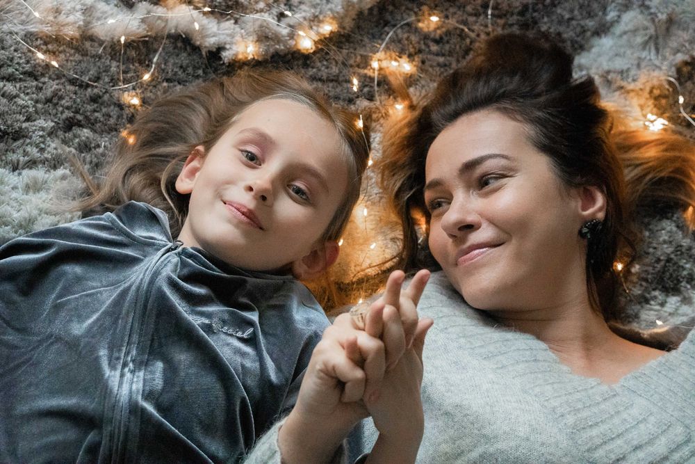 Mother and daughter lie on the carpet and enjoy the festive mood.