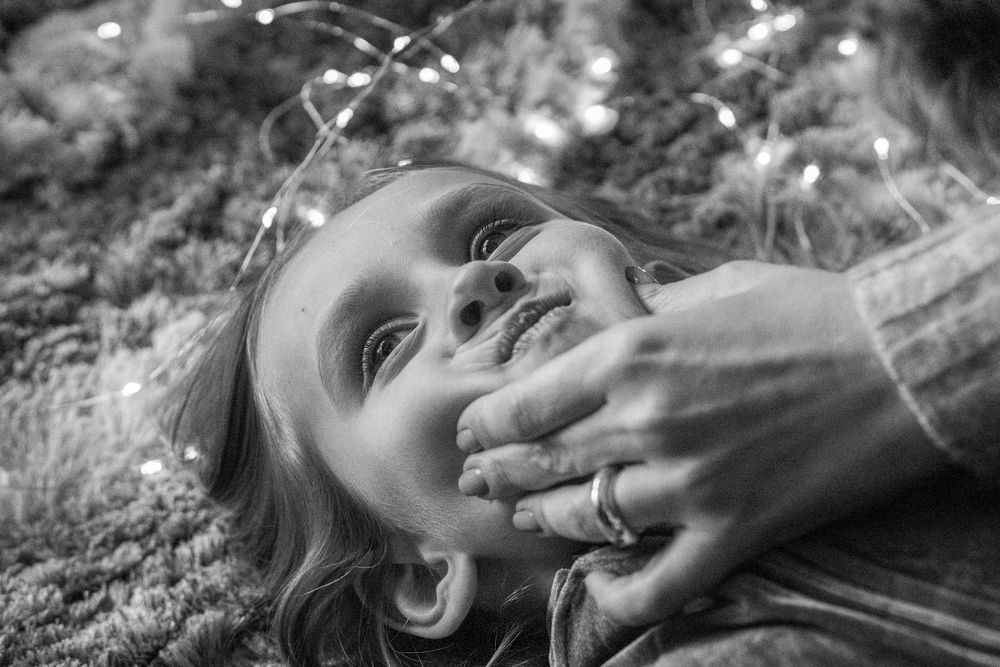 A girl plays with her mother on the carpet.