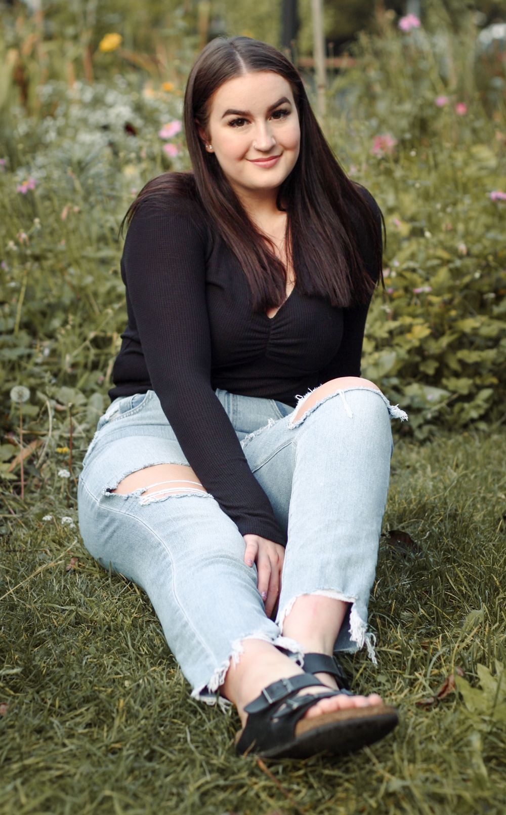 Girl posing on grass with flowers at Manito Park Spokane Washington for Senior photos