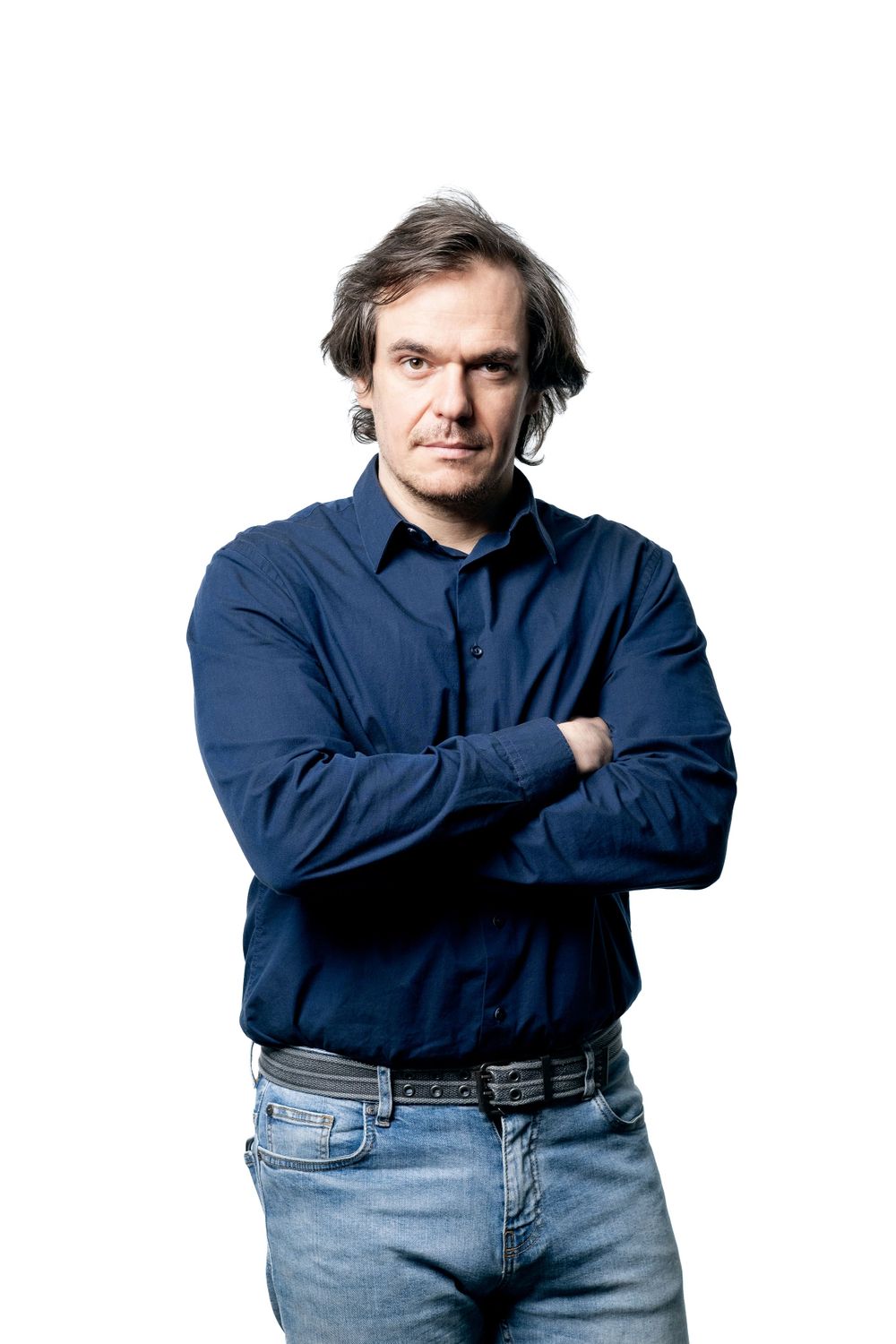 Professional headshot of person in navy shirt and jeans against white background.