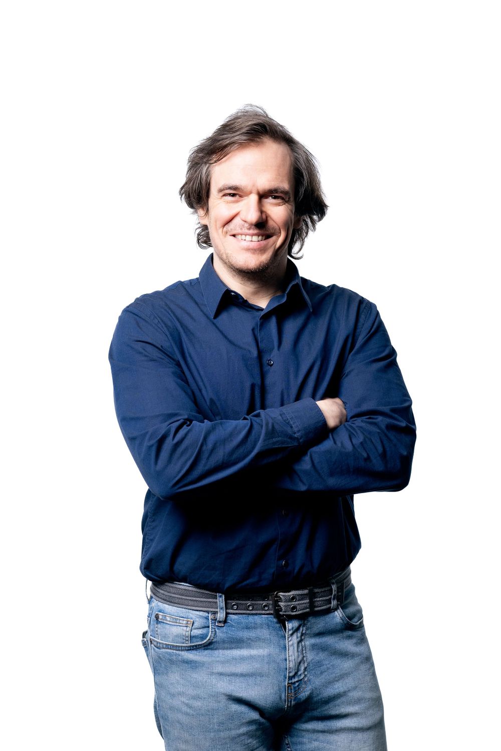 Studio portrait of person in business casual attire smiling against white background.