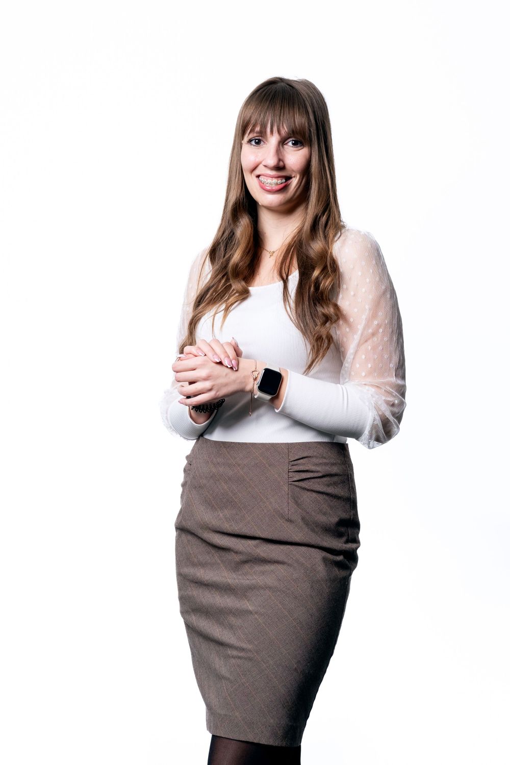 Business portrait of person in white blouse and grey pencil skirt against white background.