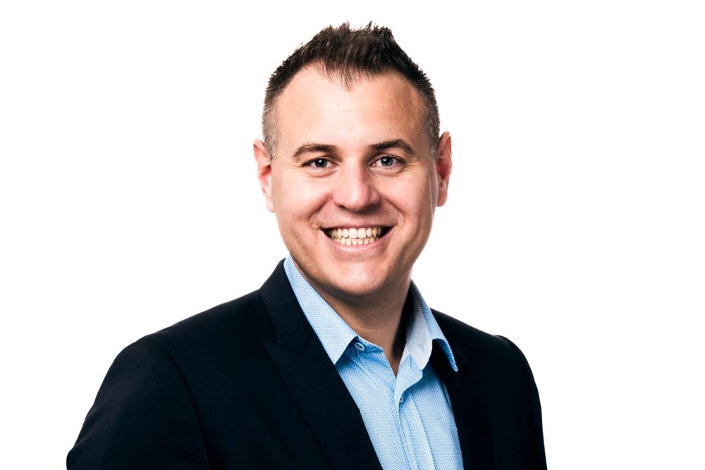 Corporate headshots series featuring a person in light blue shirt and dark jacket.