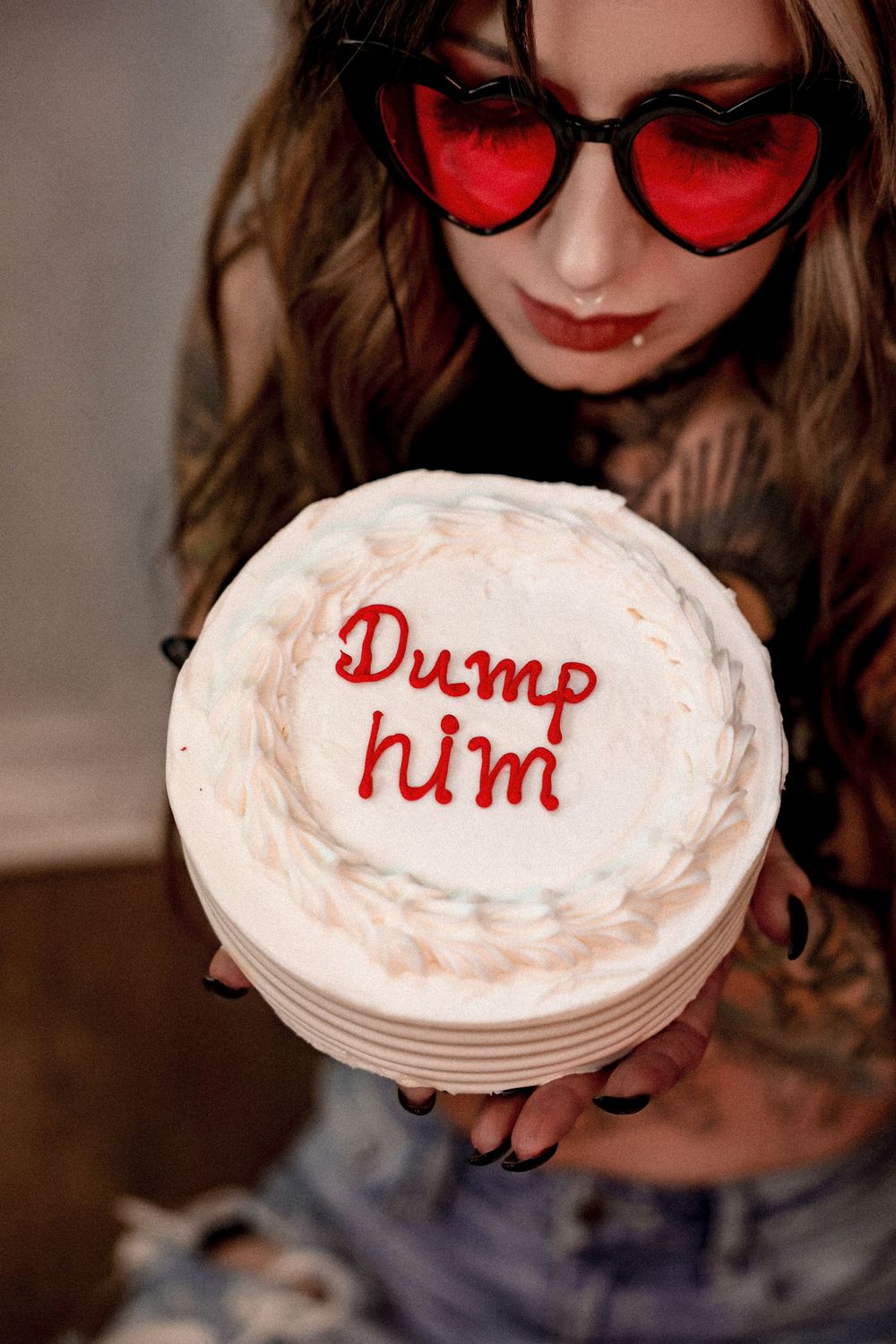 Close-up of heart sunglasses and white cake with red text reading 'Dump him'.