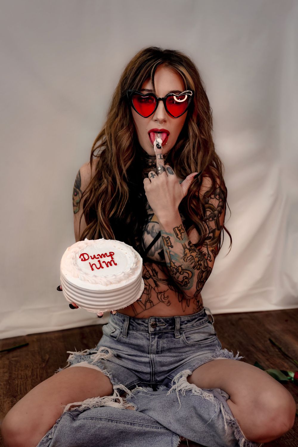 Edgy portrait with red heart sunglasses and decorated white cake.