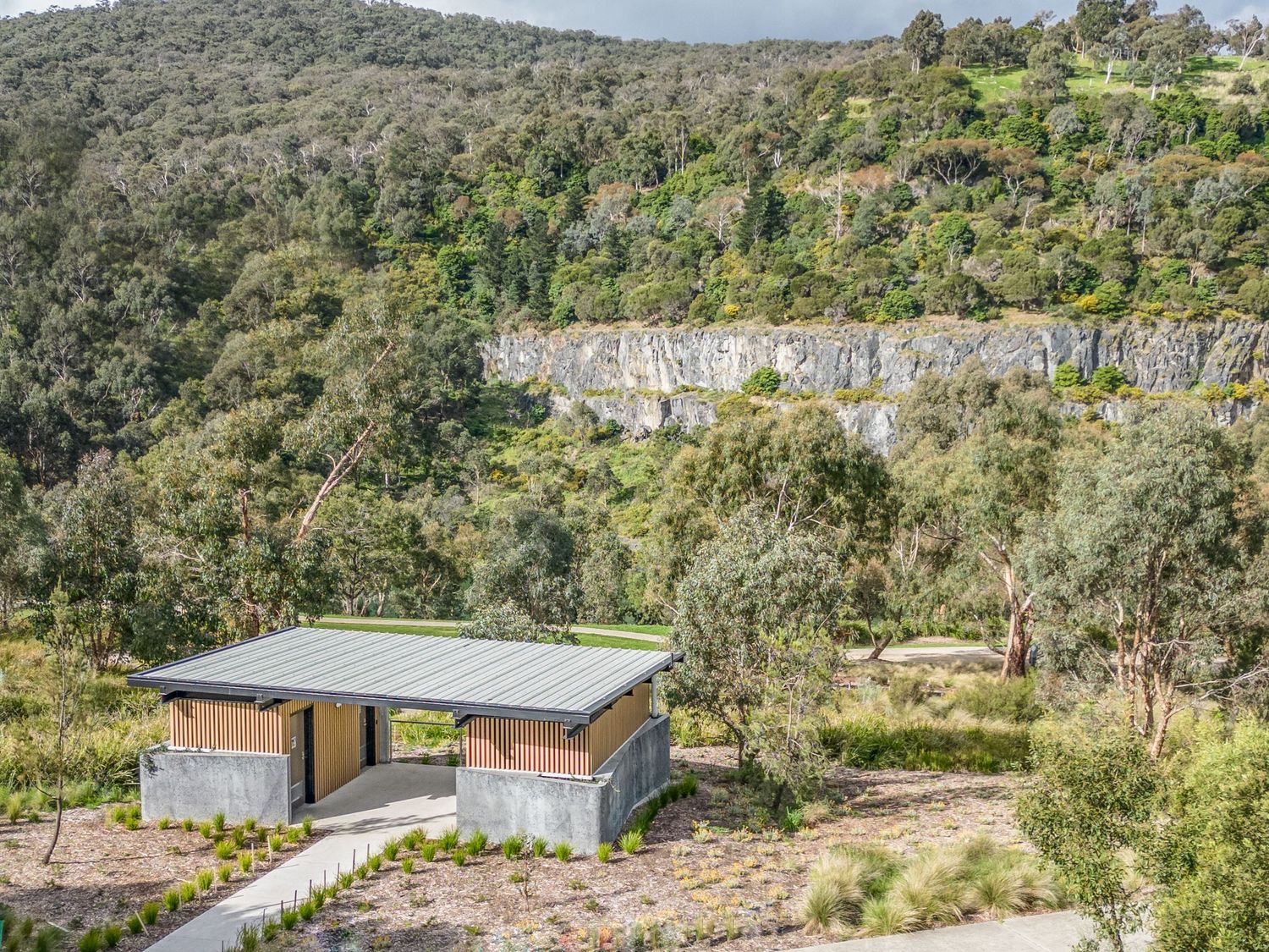 Modern building with flat roof design perched on hillside surrounded by native vegetation.