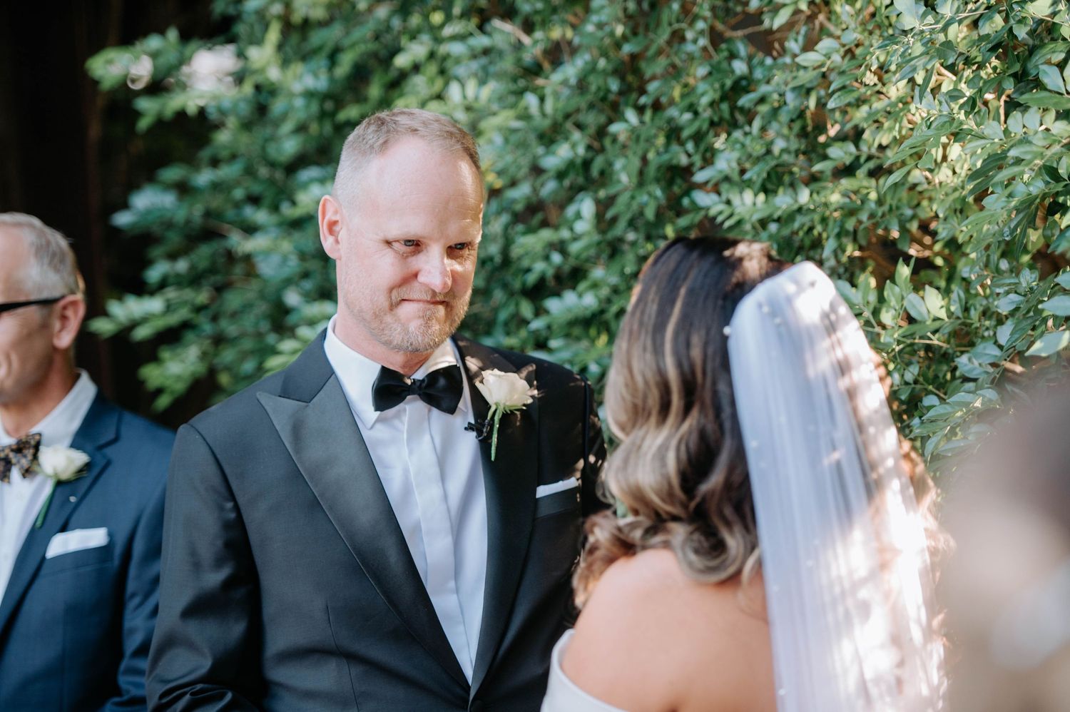 Emotional wedding ceremony moment under greenery and natural light.